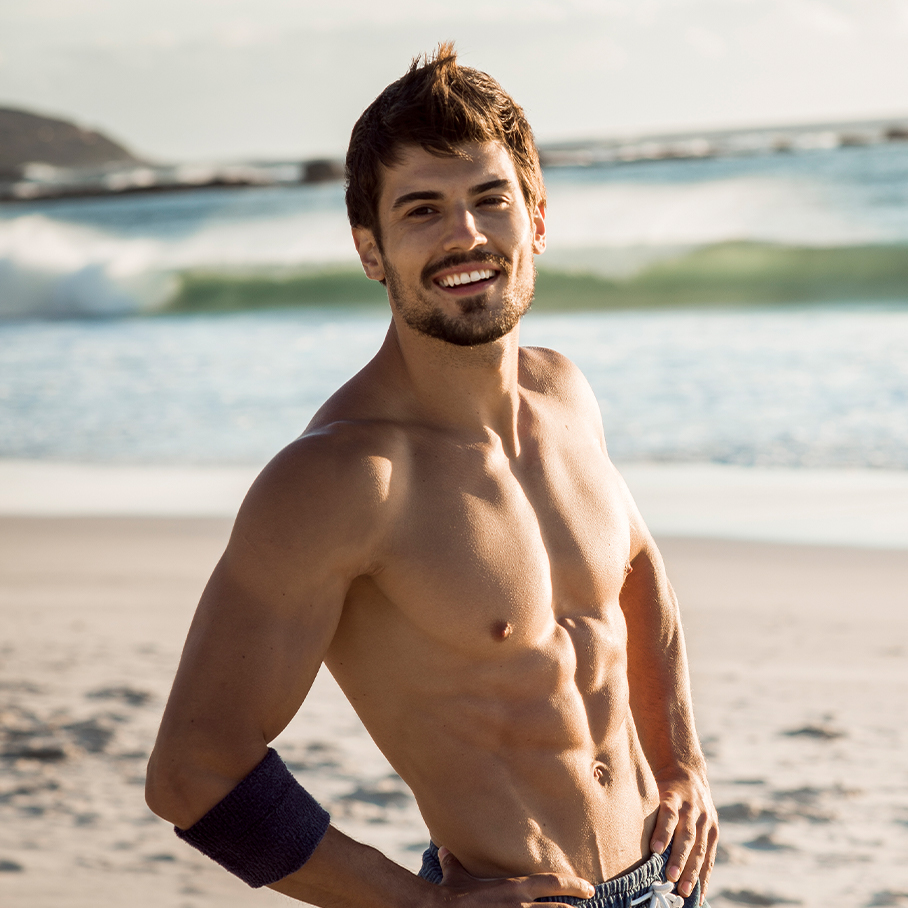 Man on the beach with sculpted abs after CoolTone treatment in Colts Neck, NJ